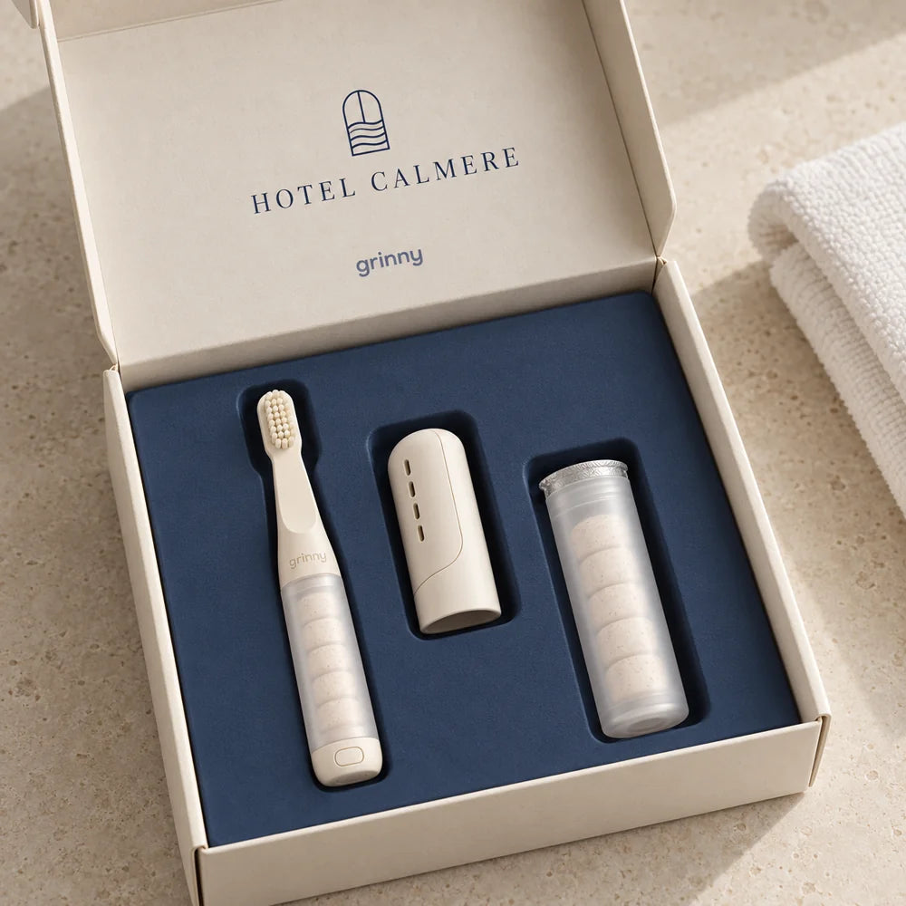 Hotel Calmere concept: an off-white miniature grinny brush and cream hotel amenity packaging with Hotel Calmere branding