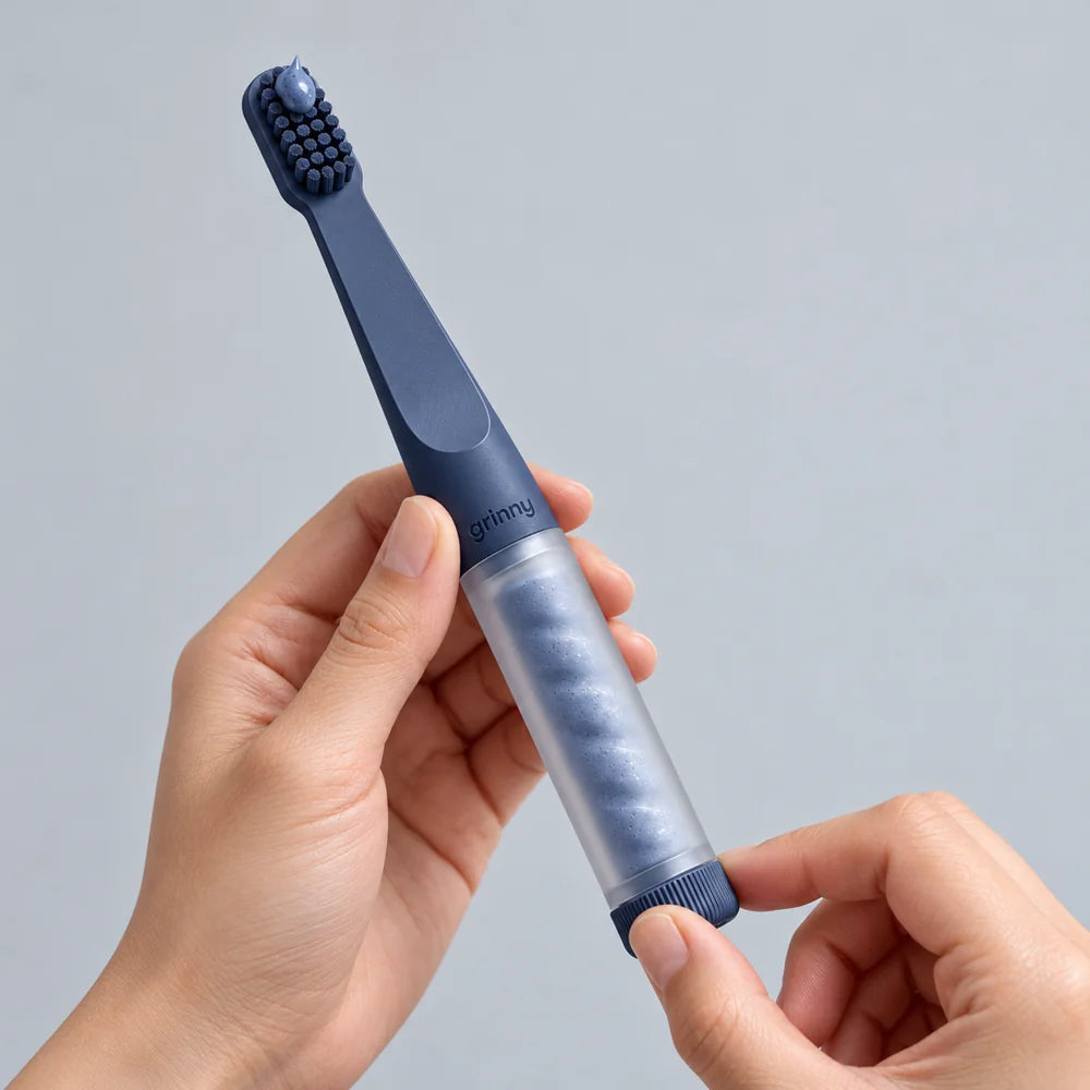 A hand twists the navy Paste Brush base, dispensing a small amount of paste at the bristles